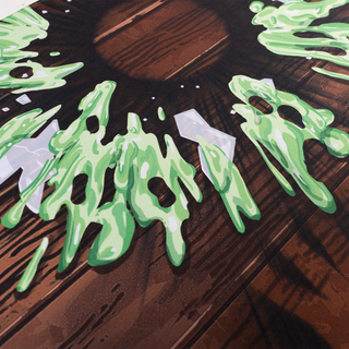 GMM Experiment desk mat with green slime and broken glass on a wood surface.