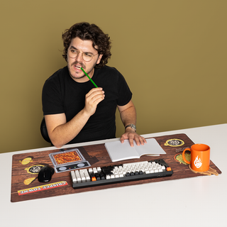 GMM Deep Fried Desk Mat with deep fryer, keyboard, mouse, notebook, and mug with a flame logo. Crispee Towne text.