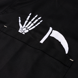 Angled view of an Apron & Pin Bundle. Black apron with skeleton hand and scythe design, and pin.