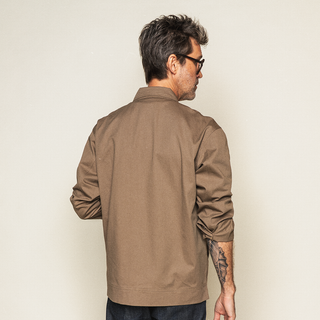 Brown Mythical Work Jacket in side view with YKK zipper, metal snaps, and checkerboard motif patch pockets.