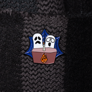 Spooky GMM Desk Pin of the Month with two ghosts, a table, and a candle.