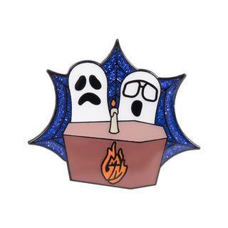 Spooky GMM Desk Pin of the Month with two ghosts, one with glasses, behind a coffin with a candle on top, over a blue glitter background.