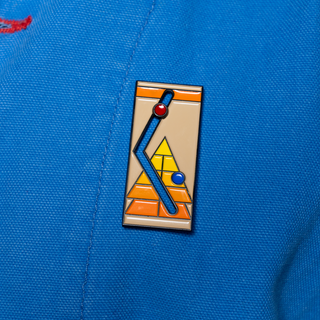 Sliding Shuffleboard Pin of the Month featuring geometric figures and red and blue balls on a beige background.
