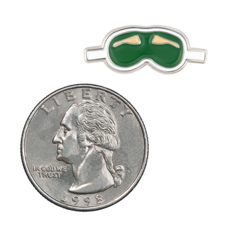 Angled view of a Rhett & Link Blindfold Mini Pin of the Month, with green and gold ski goggles, next to a quarter.