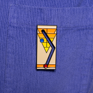 Sliding shuffleboard pin of the month featuring geometric design with a blue and red ball on a blue corduroy.